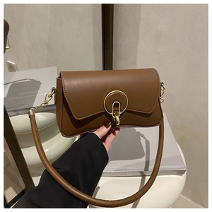 Close-up of caramel rectangle shoulder bag featuring a prominent gold round metal buckle