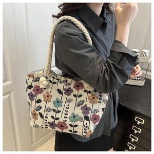 Close-up of floral canvas tote bag with thick rope handles worn by a female model