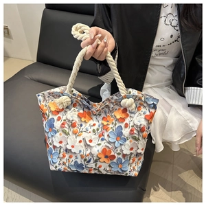 Detail of floral tote bag showing colorful 3D prints and white rope handles