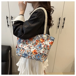 Detail of floral embroidery on a white tote bag with hand-woven rope shoulder straps