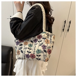 Detail of floral tapestry tote bag with thick white rope handles and large knot accents
