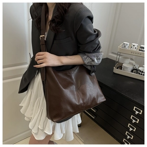 Detail of dark brown tote bag with wide shoulder strap and gold buckle adjustment