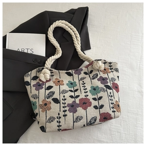 Detail of vintage floral print on beige woven tote with rope handles and artsy props