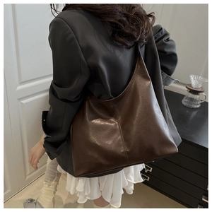 Detail view of deep brown oversized tote bag with premium leather texture and wide strap
