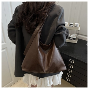 Detail of a large dark brown faux leather hobo bag featuring wide straps and soft texture