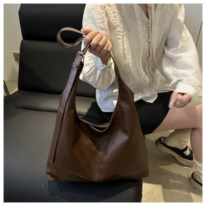 Detail of a dark brown textured leather tote bag with an adjustable wide shoulder strap