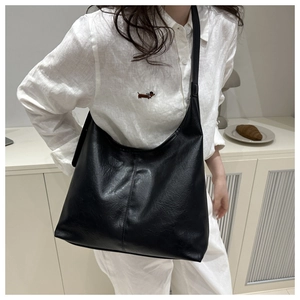Detail of black large-capacity tote bag showing vintage leather texture and wide shoulder strap