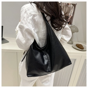 Black large capacity tote bag worn over the shoulder showing minimalist trapezoid shape