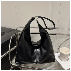 Detailed view of large black bucket bag texture on metal cart with coffee and magazine