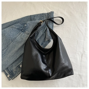 Detail of black large capacity bucket bag in glossy PU leather with adjustable strap