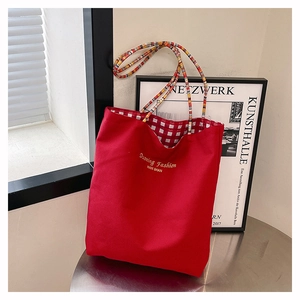Detail of red canvas tote bag with red and white gingham lining and braided rope handles