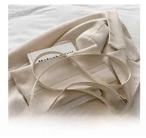 Detail of cream leather shoulder bag with V-shaped metal buckle and slim strap