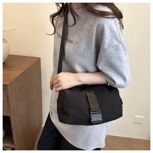 Detailed side view of the black Oxford cloth crossbody bag worn on a casual outfit