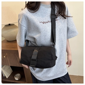 Close-up of black oxford cloth cylinder crossbody bag with adjustable strap and buckle