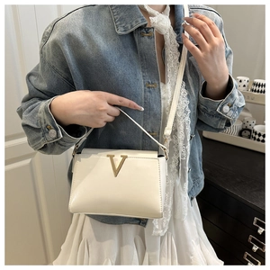 White leather handbag featuring a golden V-shaped buckle and adjustable shoulder strap