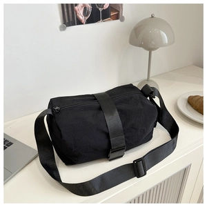 Detail of black nylon cylinder bag showing the plastic buckle strap and top zipper closure