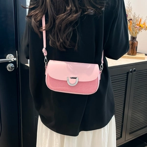 Pink patchwork crossbody bag with metallic D-ring buckle shown on a model's shoulder