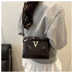 Detailed back view of a dark brown patent leather crossbody bag with a gold V-shape clasp