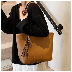 Detail of earthy brown tote bag with fashion lettering and tennis racket pendant
