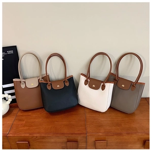 Détail de quatre sacs cabas chics en marron, noir, blanc et gris avec logo doré
