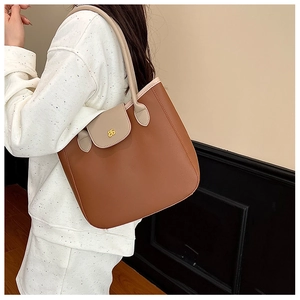 Détail d'un grand cabas en cuir grainé marron avec anses beige et logo en métal doré