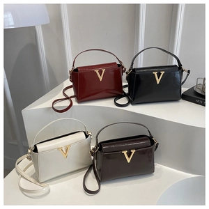 Detailed view of glossy patent leather handbags in four colors with gold V-shaped logo