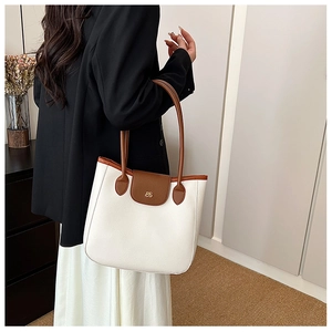 Détail d'un sac cabas bicolore en cuir blanc avec des anses marron au style minimaliste