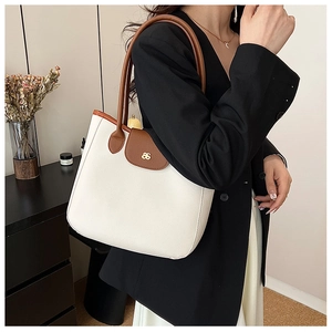 Détail d'un sac cabas en cuir beige et marron avec logo en métal doré sur le rabat