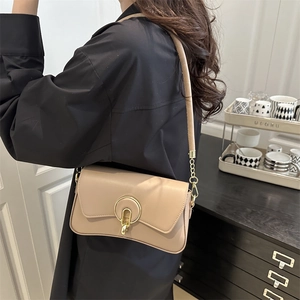 Retro beige leather crossbody bag with golden round lock on model in minimalist interior