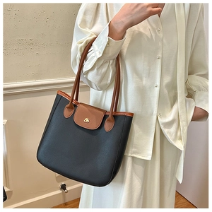 Détail du sac cabas minimaliste noir et marron avec texture cuir et logo doré élégant