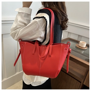 Detail of red lychee pattern tote bag with white contrast stitching and side straps