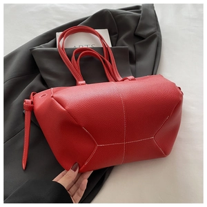 Detail of red lychee grain leather tote bag with white contrast stitching and soft handles