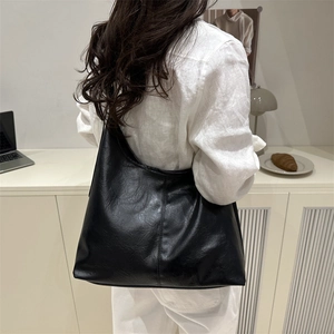 Minimalist black large capacity leather tote bag worn by model in a modern room