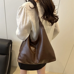 Brown large capacity leather tote bag with lychee texture shown on model shoulder