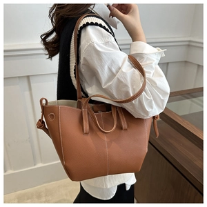 Detail of brown leather tote bag with white contrast stitching and dual handle design