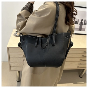 Detail of black pebbled leather tote bag with white contrast stitching and shoulder straps