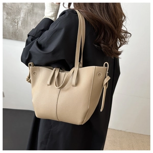 Detail of light beige PU leather tote bag with side ribbon accents shown on shoulder
