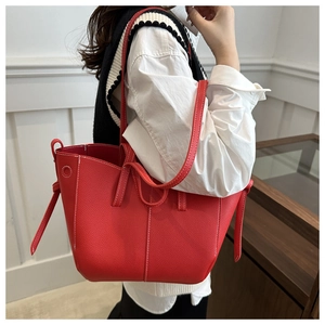 Detail of red PU leather tote bag with white stitching and decorative leather straps