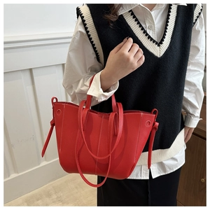 Detail of red tote bag with contrast white stitching and knot decor on shoulder strap