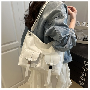 Detail of white patent leather tote bag showing glossy texture and dual front pockets