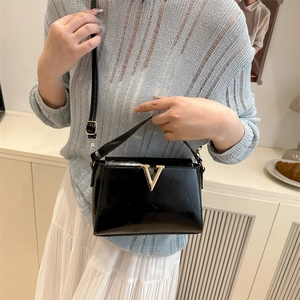 Elegant black patent leather handbag with gold V-shaped logo and adjustable strap