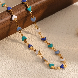 Detailed shot of gold chain necklace with colorful enamel heart charms in multiple hues