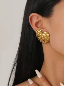 Close-up of vintage gold hammered heart button earrings worn on a female ear