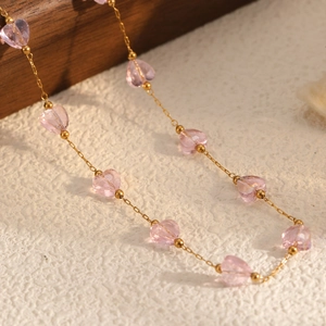 Gold chain necklace featuring pink crystal hearts and small beads for a summer look