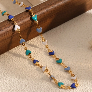 Elegant gold chain necklace with colorful oil-dripped heart pendants on wood stand