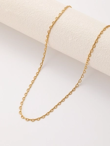 Detail of a thin gold stainless steel cable chain necklace draped over a textured pedestal