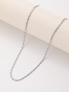 Detailed view of silver stainless steel cable link chain draped over a minimalist white prop