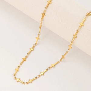 Collier chaîne à croix plaqué or 14 carats sur un support de bijoux blanc minimaliste