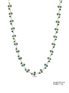 Detail view of gold cherry chain with blue glitter beads and green enamel leaves