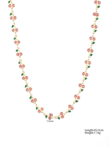 Macro detail of gold 304 stainless steel chain with pink cherry enamel charms